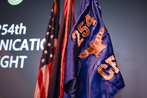 The brand-new guidon and flag for the 254th Communications Flight (CF) stands amongst the Guam and American flags at the Meehan Theatre, Andersen Air Force Base, Guam, June 7, 2025.