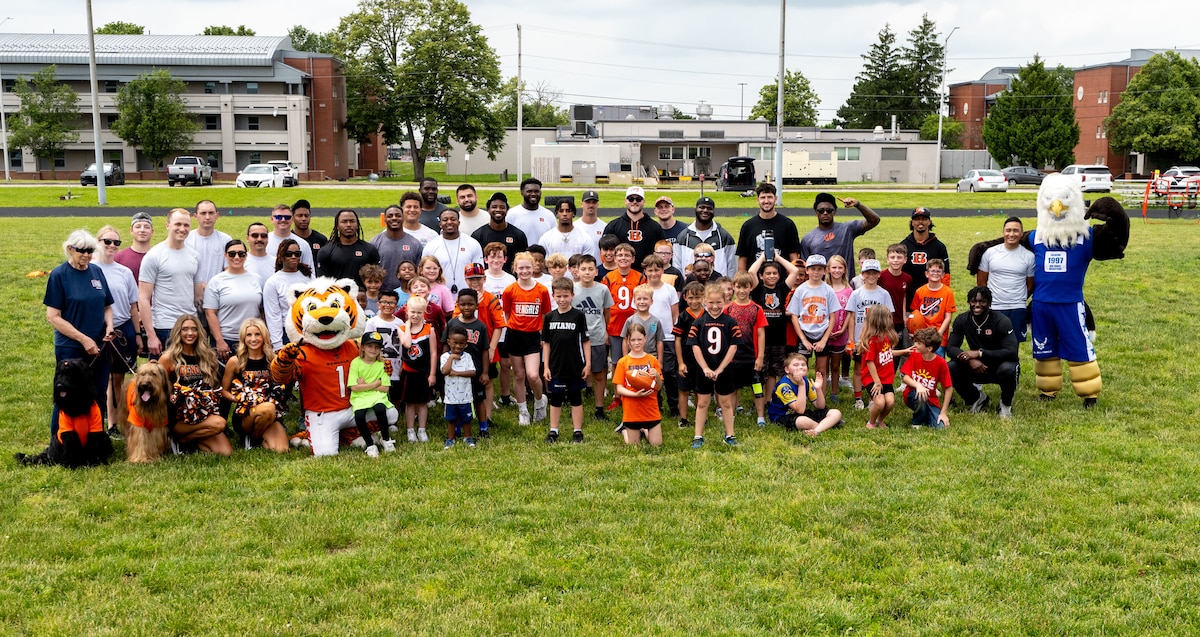 Cincinnati Bengals rookies, military children and volunteers pose for a group photo on a football field.