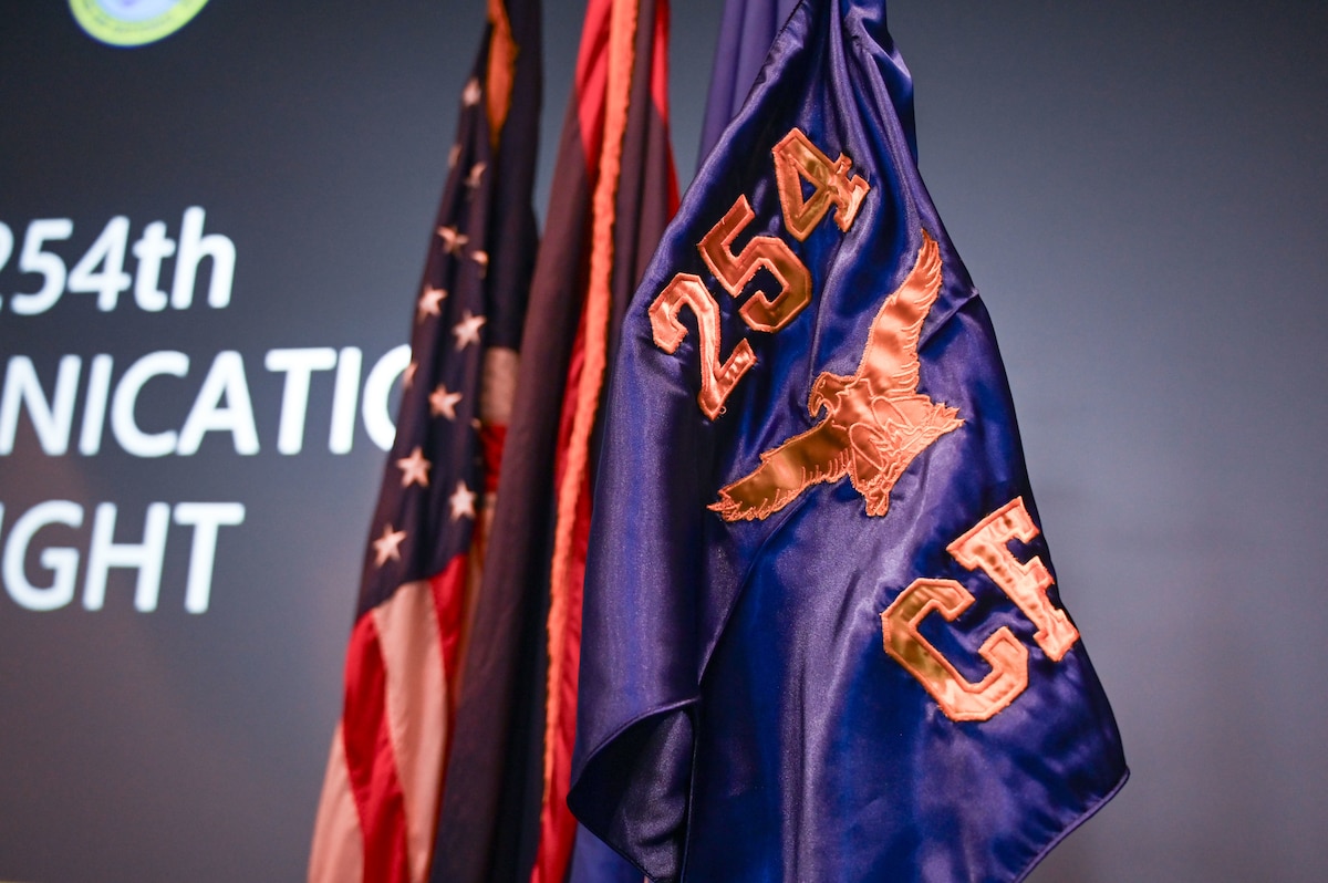 The brand-new guidon and flag for the 254th Communications Flight (CF) stands amongst the Guam and American flags at the Meehan Theatre, Andersen Air Force Base, Guam, June 7, 2025.