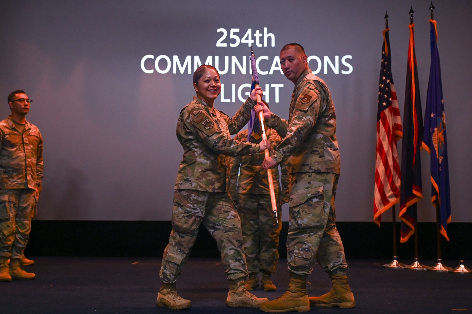 U.S. Air Force Col. Veronica Reyes, passes the guidon to Capt. Tommy Joe Rivera, 254th Communications Flight (CF) commander on Andersen Air Force Base, Guam, June 7, 2025.