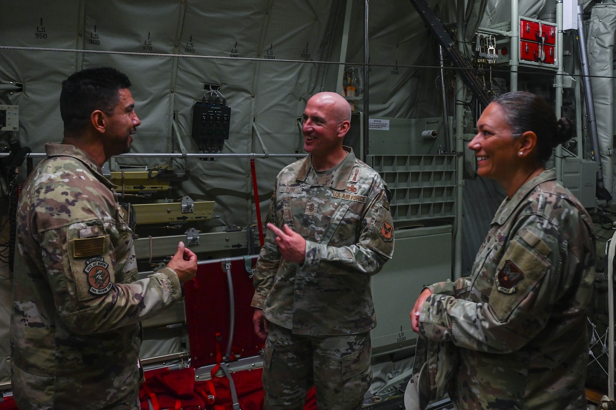 Service members talk in the back of an aircraft.