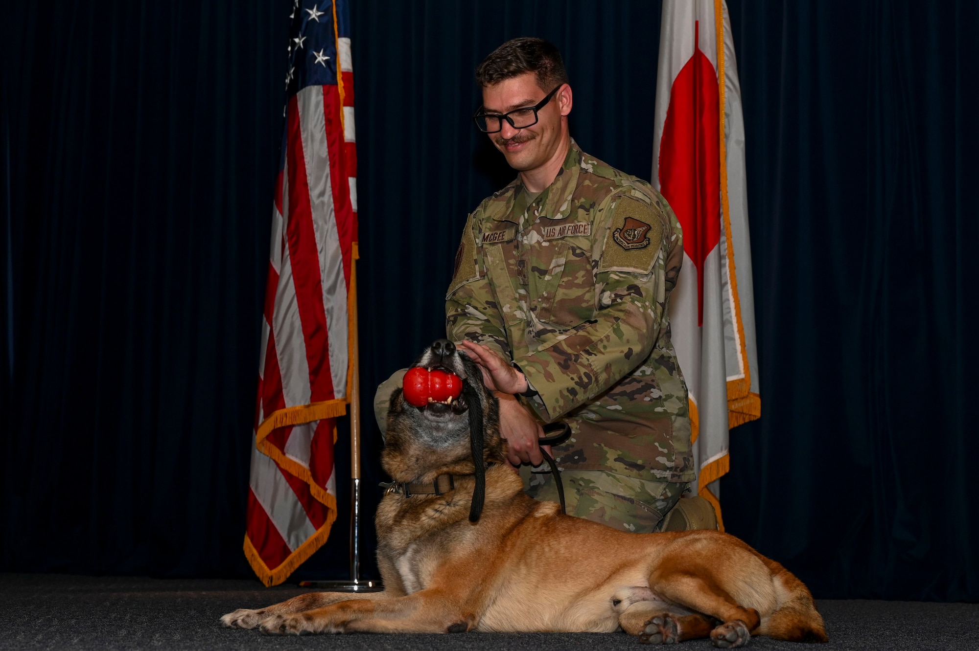 A MWD and his handler kneel on stage.