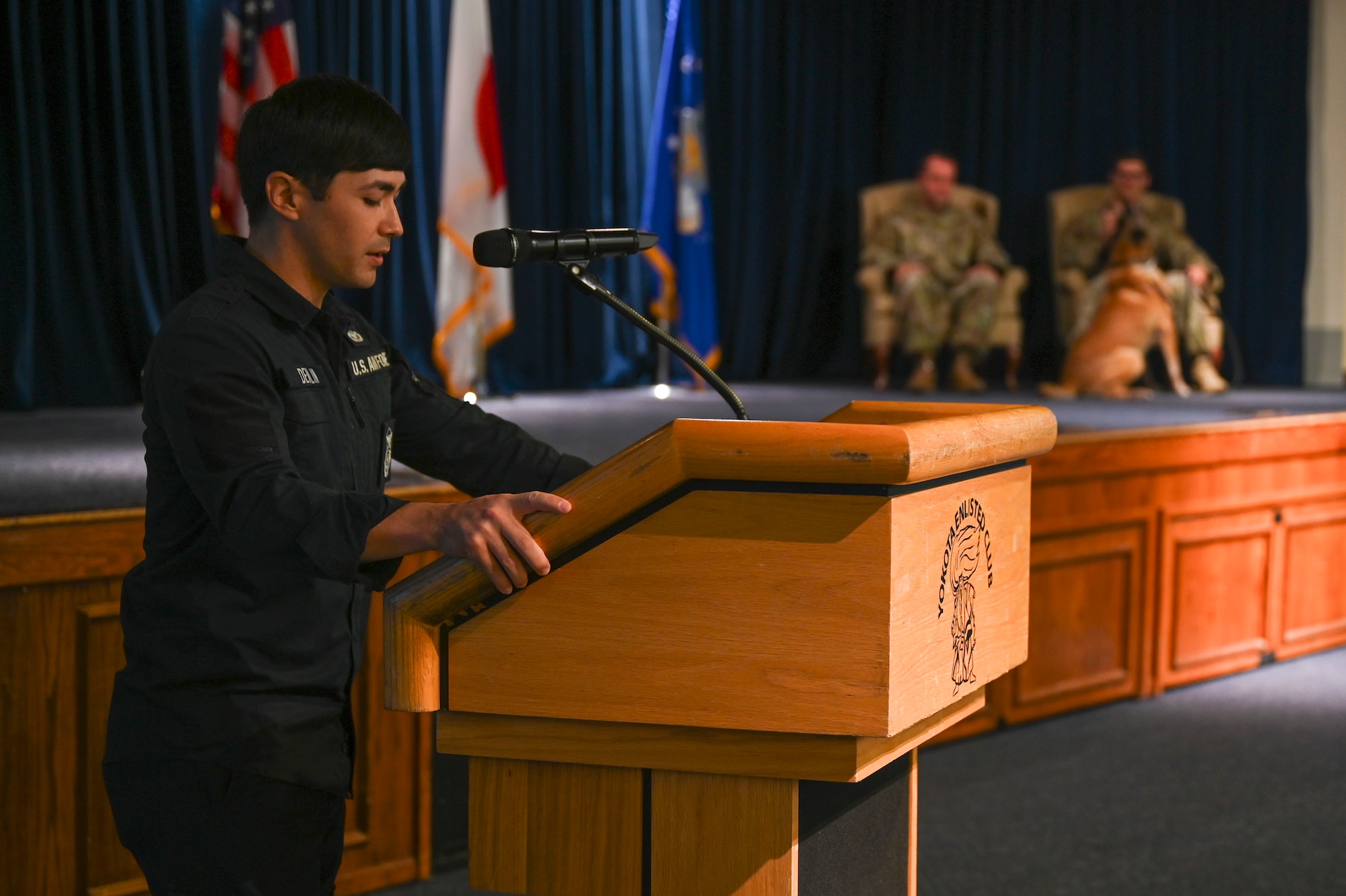 A MWD handler reads a poem at a podium.