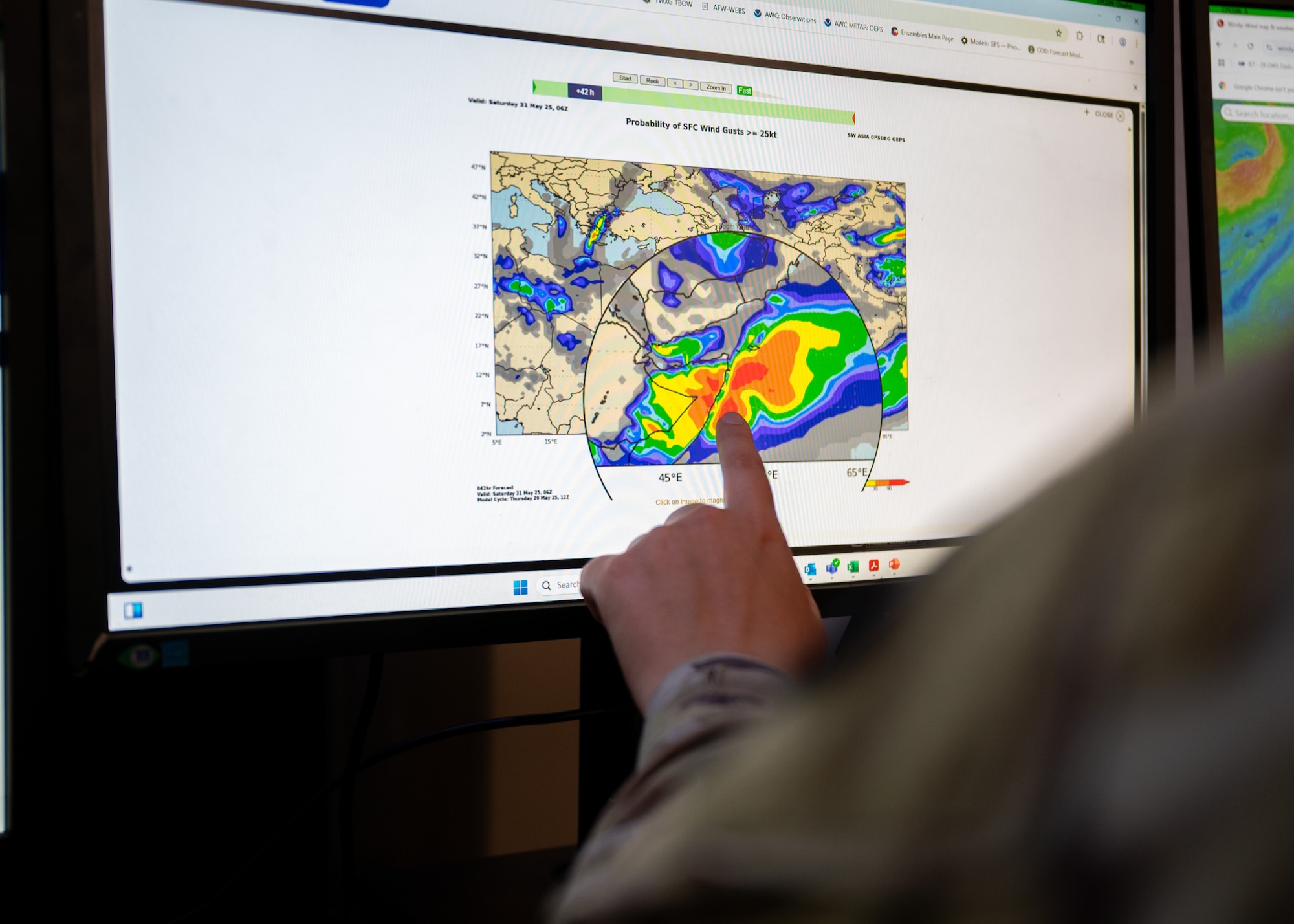 Airman points at a weather map on a computer screen