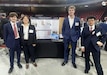 Northeastern University students Alexander Patten, Erica Lu, Logan Kane, and Johan Cho stand by their project display during their senior Capstone Day at Matthews Arena April 15, 2025. The team celebrated the culmination of a yearlong partnership with engineers from the Army Combat Capabilities Development Command (DEVCOM and Personnel Airdrop Systems team in developing modernized equipment used during parachute quality assurance inspections. (Photo courtesy of Natick Soldier Systems Center)