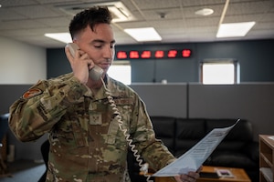 a service member on the phone holding up a piece of paper