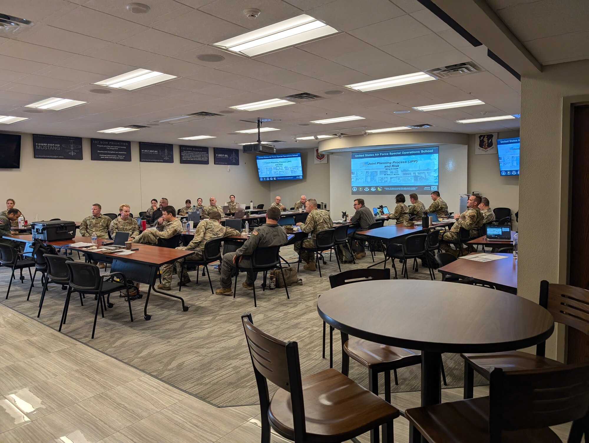 Uniformed members sit at a desk in a conference room.