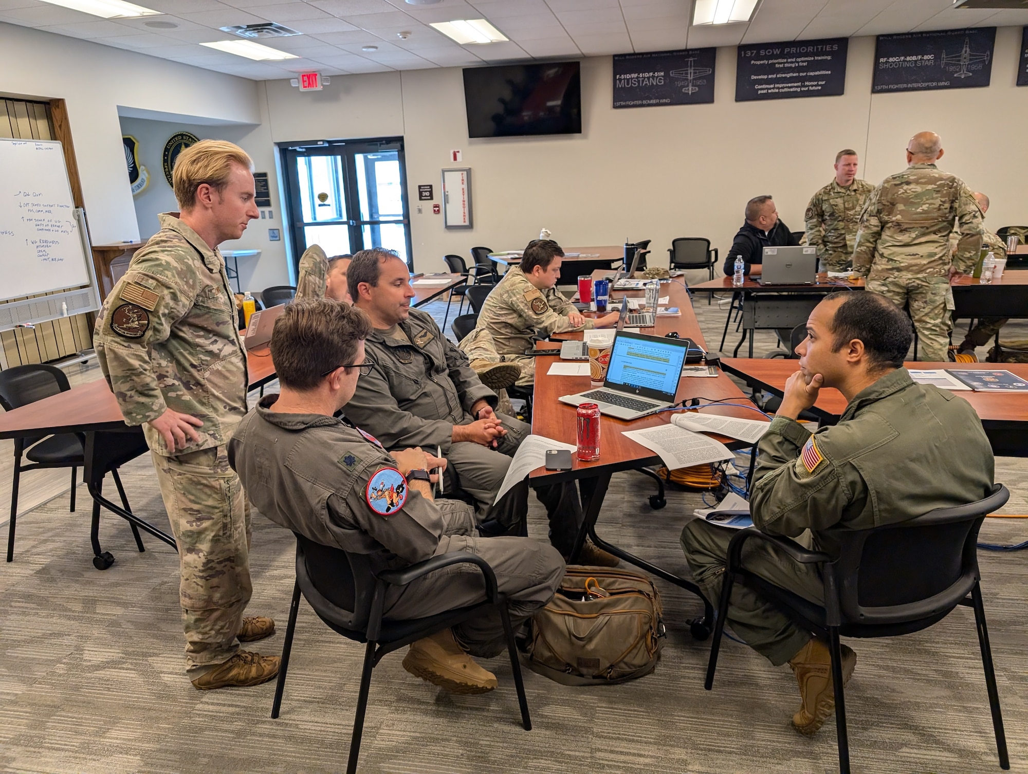 Uniformed members sit at a desk in a conference room.