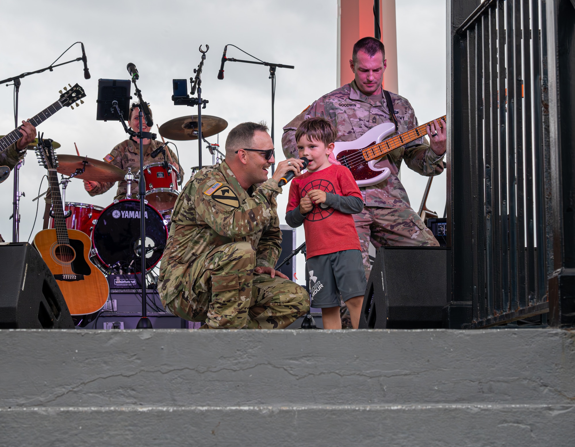 U.S. Army Staff. Sgt. Jeffery McCormick, Training Doctrine and Command Rock Band lead vocalist, sings alongside a small child.