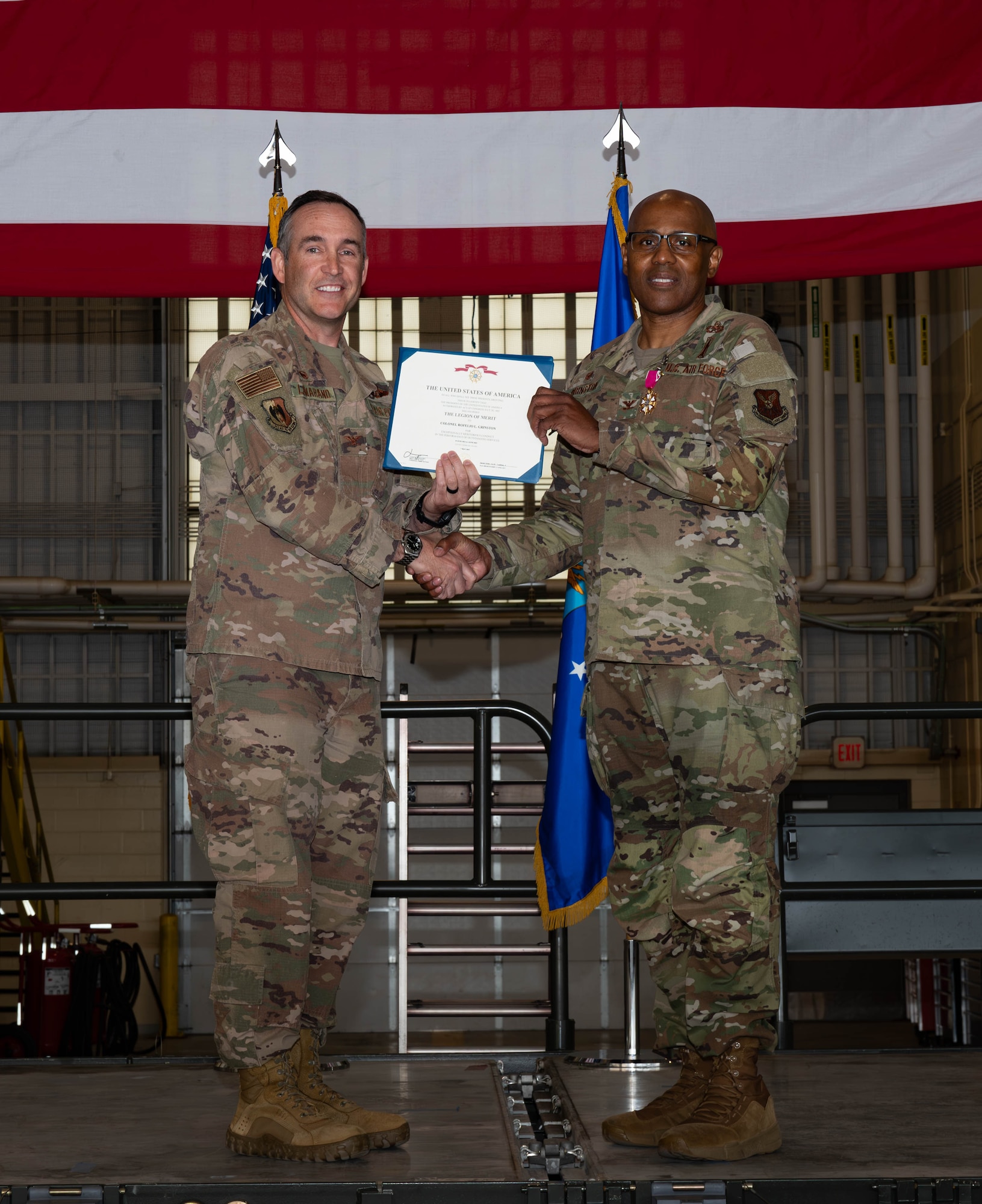 U.S. Air Force Col. Jesse Lamarand, 5th Bomb Wing commander, presents Col. Rofelio Grinston, 5th Maintenance Group (5MXG) commander, the meritorious service medal during the 5MXG change of command ceremony at Minot Air Force Base, North Dakota, June 4, 2025. During the ceremony, Grinston relinquished command to Col. Jesse Lamarand. (U.S. Air Force photo by Senior Airman Alex Nottingham)