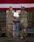 U.S. Air Force Col. Jesse Lamarand, 5th Bomb Wing commander, presents Col. Rofelio Grinston, 5th Maintenance Group (5MXG) commander, the meritorious service medal during the 5MXG change of command ceremony at Minot Air Force Base, North Dakota, June 4, 2025. During the ceremony, Grinston relinquished command to Col. Jesse Lamarand. (U.S. Air Force photo by Senior Airman Alex Nottingham)