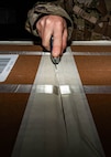 Airman 1st Class Emily Leavitt, Traffic Management Office inbound cargo technician, opens a piece of cargo at Minot Air Force Base, North Dakota, Jun 3, 2025. The Traffic Management Operations team is responsible for coordinating the shipment of cargo, equipment, and personnel to support military operations. (U.S. Air Force Senior Airmen Alex Nottingham)