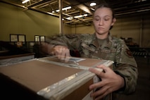 Airman 1st Class Emily Leavitt, Traffic Management Office inbound cargo technician, opens a piece of cargo at Minot Air Force Base, North Dakota, Jun 3, 2025. Every box is opened and inspected to count the quantity of cargo inside. (U.S. Air Force Senior Airmen Alex Nottingham)
