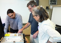 JOINT BASE SAN ANTONIO-FORT SAM HOUSTON – (May 22, 2025) – SteriO3 CEO Dr. Steve Hughes (center) delivered the third generation of the Rugged Ozone Sterilization System Model M1 (ROSS M1) to Naval Medical Research Unit (NAMRU) San Antonio principal investigator Andres Martinez Murillo and research scientist Tarea Burton at the Battlefield Health and Trauma Research Institute.  NAMRU San Antonio researcher will test the flexibility, portability, and efficiency of the ROSS M1 against multiple species of harmful microorganisms helps to promote and maintain medical and military readiness, especially in austere environments. Navy Medicine Research & Development (NMR&D) employs highly qualified medical researchers and works alongside a wide range of research and development partners to keep abreast of best practices and advances in medical knowledge on behalf of Navy Medicine to increase warfighter lethality. NAMRU San Antonio, part of NMR&D, conducts gap-driven combat casualty care, craniofacial, and directed energy research in support of Navy, Marine Corps and joint U.S. warfighter health readiness and lethality while engaged in routine and expeditionary operations. (U.S. Navy Photo by Burrell Parmer, NAMRU San Antonio Public Affairs/Released)