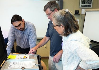 JOINT BASE SAN ANTONIO-FORT SAM HOUSTON – (May 22, 2025) – SteriO3 CEO Dr. Steve Hughes (center) delivered the third generation of the Rugged Ozone Sterilization System Model M1 (ROSS M1) to Naval Medical Research Unit (NAMRU) San Antonio principal investigator Andres Martinez Murillo and research scientist Tarea Burton at the Battlefield Health and Trauma Research Institute.  NAMRU San Antonio researcher will test the flexibility, portability, and efficiency of the ROSS M1 against multiple species of harmful microorganisms helps to promote and maintain medical and military readiness, especially in austere environments. Navy Medicine Research & Development (NMR&D) employs highly qualified medical researchers and works alongside a wide range of research and development partners to keep abreast of best practices and advances in medical knowledge on behalf of Navy Medicine to increase warfighter lethality. NAMRU San Antonio, part of NMR&D, conducts gap-driven combat casualty care, craniofacial, and directed energy research in support of Navy, Marine Corps and joint U.S. warfighter health readiness and lethality while engaged in routine and expeditionary operations. (U.S. Navy Photo by Burrell Parmer, NAMRU San Antonio Public Affairs/Released)