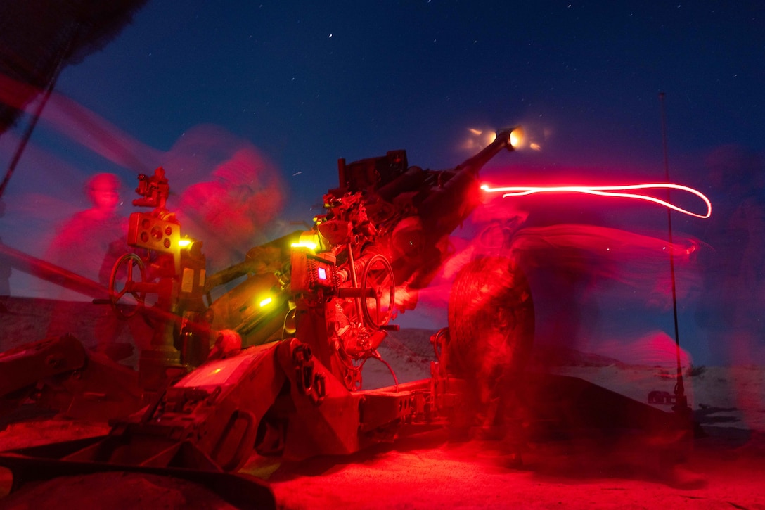 Blurred Marines load and fire a weapon illuminated by red streaks and neon lights under a starry night sky.