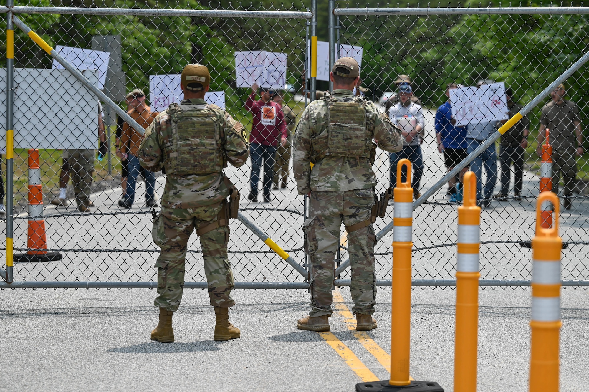 Airmen stand in front of gate.