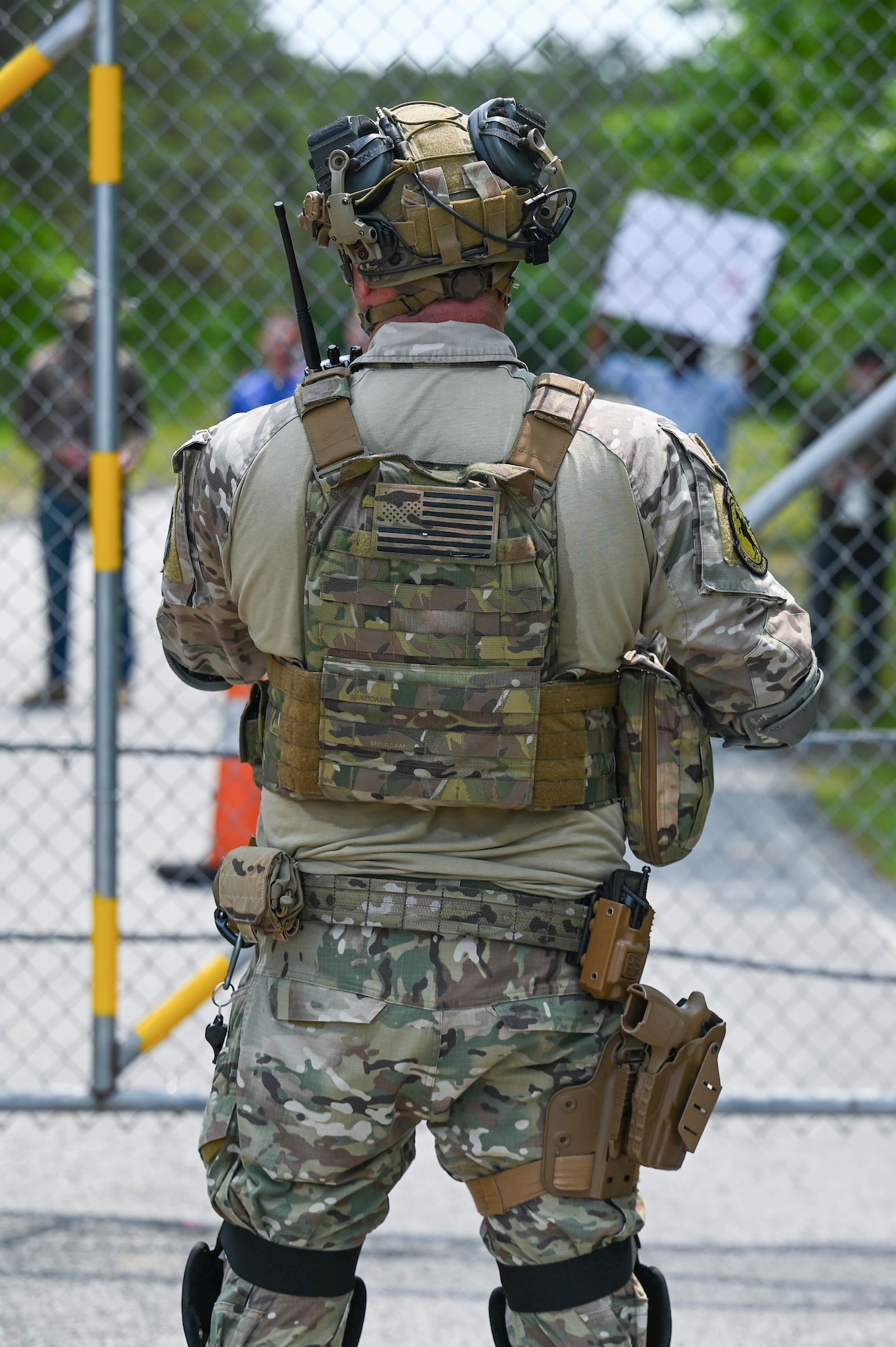 Airman stands in front of gate.