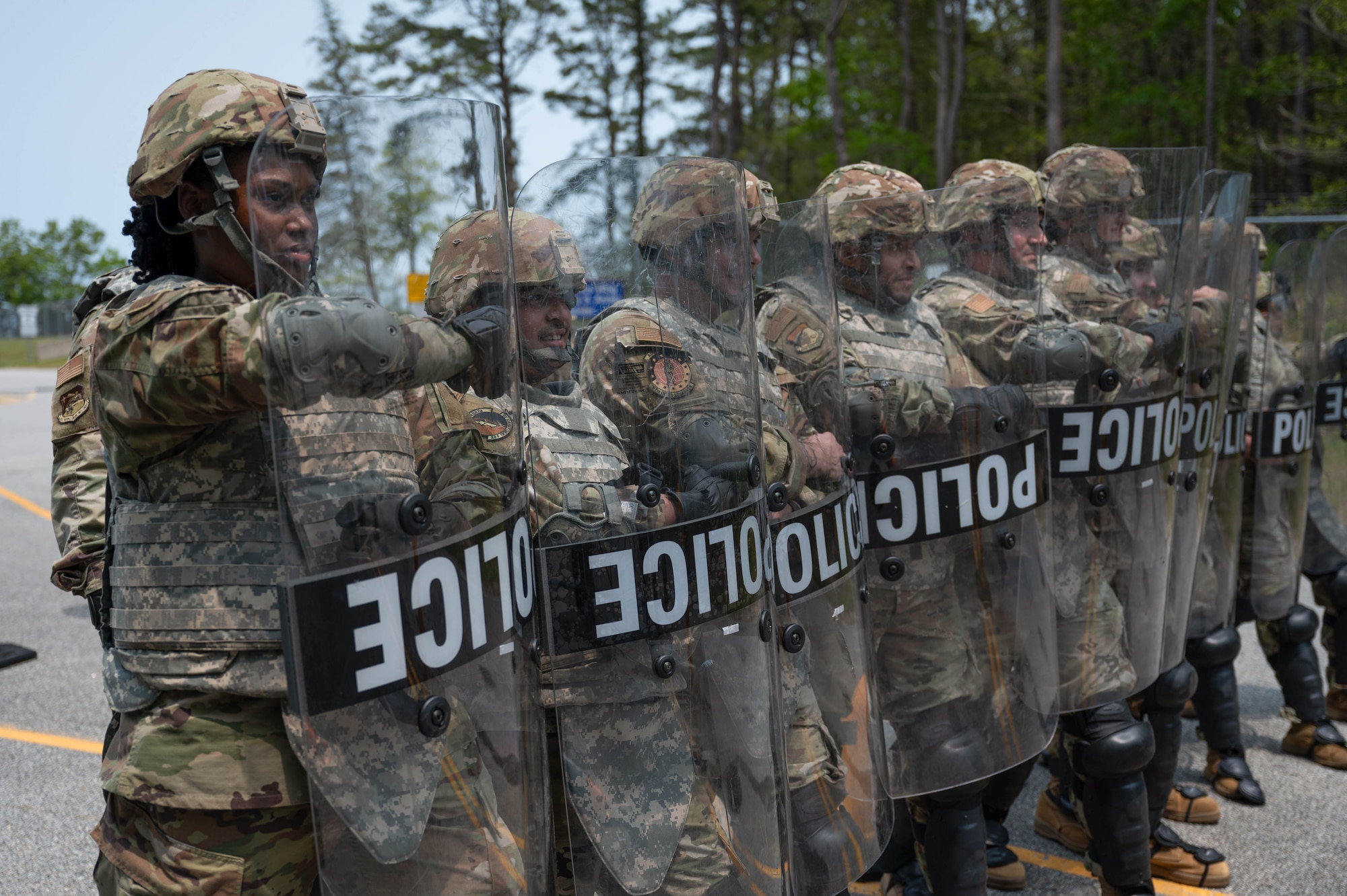 Airmen hold riot control shields.