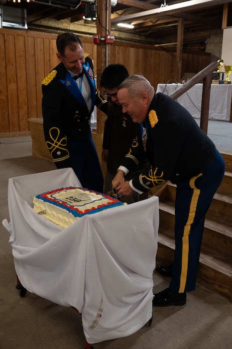 U.S. Army Chief Warrant Officer 5 James O'neill, 344th Military Intelligence Battalion chief instructor, and Spc. Antonio Martinez, 344th MIB S1 clerk, slice the cake with Lt. Col. Raymond Kuderka, 344th MIB commander, during the 250th Army Birthday Ball at The Stables Block at Fort Concho, San Angelo, Texas, June 6, 2025. The cake-cutting ceremony is a birthday ball tradition that involves the eldest and youngest soldier present to signify the development of the Army since June 14, 1775. (U.S. Air Force photo by Airman 1st Class Brian Lummus)