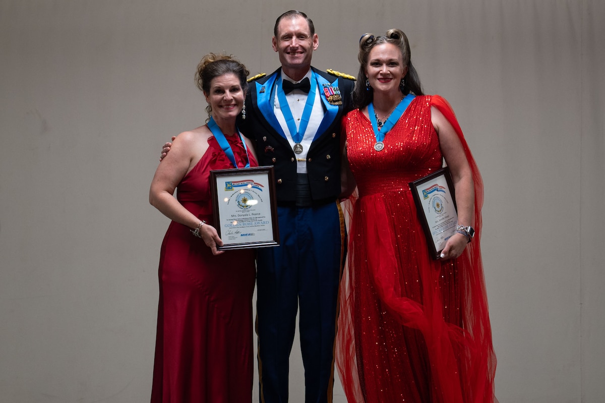 Donyala Pearce, Goodfellow Spouse and Community vice president, and Jennifer Koepl, former 3rd Infantry Brigade Family Readiness Group co-leader, pose for a group photo with U.S. Army Lt. Col. Raymond Kuderka, 344th Military Intelligence Battalion commander during the 250th Army Birthday Ball at The Stables Block at Fort Concho, San Angelo, Texas, June 6, 2025. Pearce and Koepl were awarded the Golden Rose award to recognize their spouse volunteer contributions that aided a Military Intelligence unit, activity, command or staff agency in accomplishing its mission. (U.S. Air Force photo by Airman 1st Class Brian Lummus)