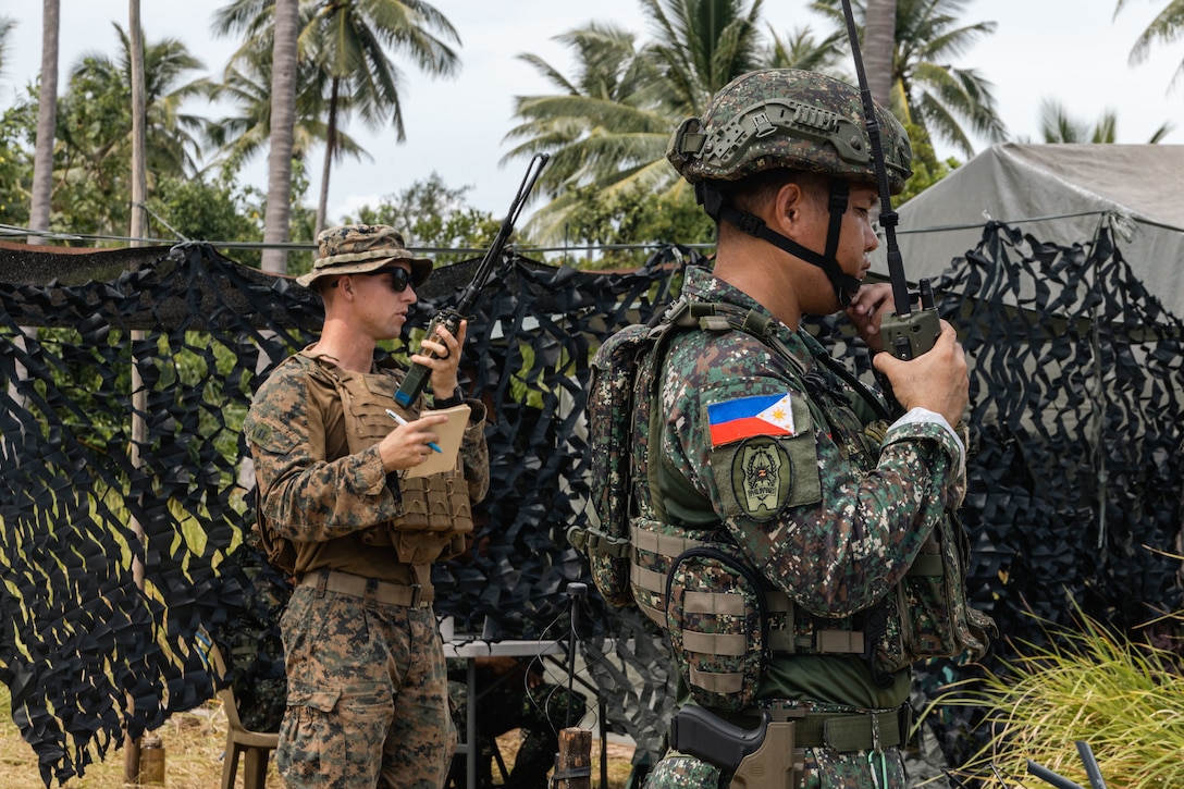 U.S. Marine Corps Capt. Holdon Loveless, a joint terminal attack controller with 1st Air Naval Gunfire Liaison Company, Marine Rotational Force – Darwin 25.3, I Marine Expeditionary Force Forward, and a Philippine Marine with 3rd Brigade, conduct fires deconfliction on radios for a counter-landing live-fire during KAMANDAG 9 at Quezon, Palawan, Philippines, June 4, 2025.