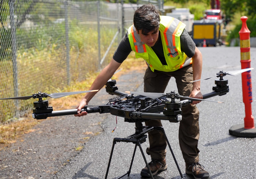 A drone operator places a heavy lift drone into launch position at the Red Hill Bulk Fuel Storage Facility (RHBFSF) in Honolulu, May 16, 2025. The drone was fitted with a laser sensor called a LiDAR, or light detection and ranging, as part of an ongoing joint effort between Navy Closure Task Force-Red Hill (NCTF-RH), the Expeditionary Warfare Center, and Naval Information Warfare Center Atlantic to create a 3D map of the RHBFSF. Charged with the safe decommissioning of the facility, NCTF-RH was established by the Department of the Navy as a commitment to the community and the environment. NCTF-RH continues to engage with the people of Hawaii, regulatory agencies, and other stakeholders as it safely and deliberately decommissions the RHBFSF. (U.S. Navy photo by Mass Communication Specialist 1st Class Glenn Slaughter)