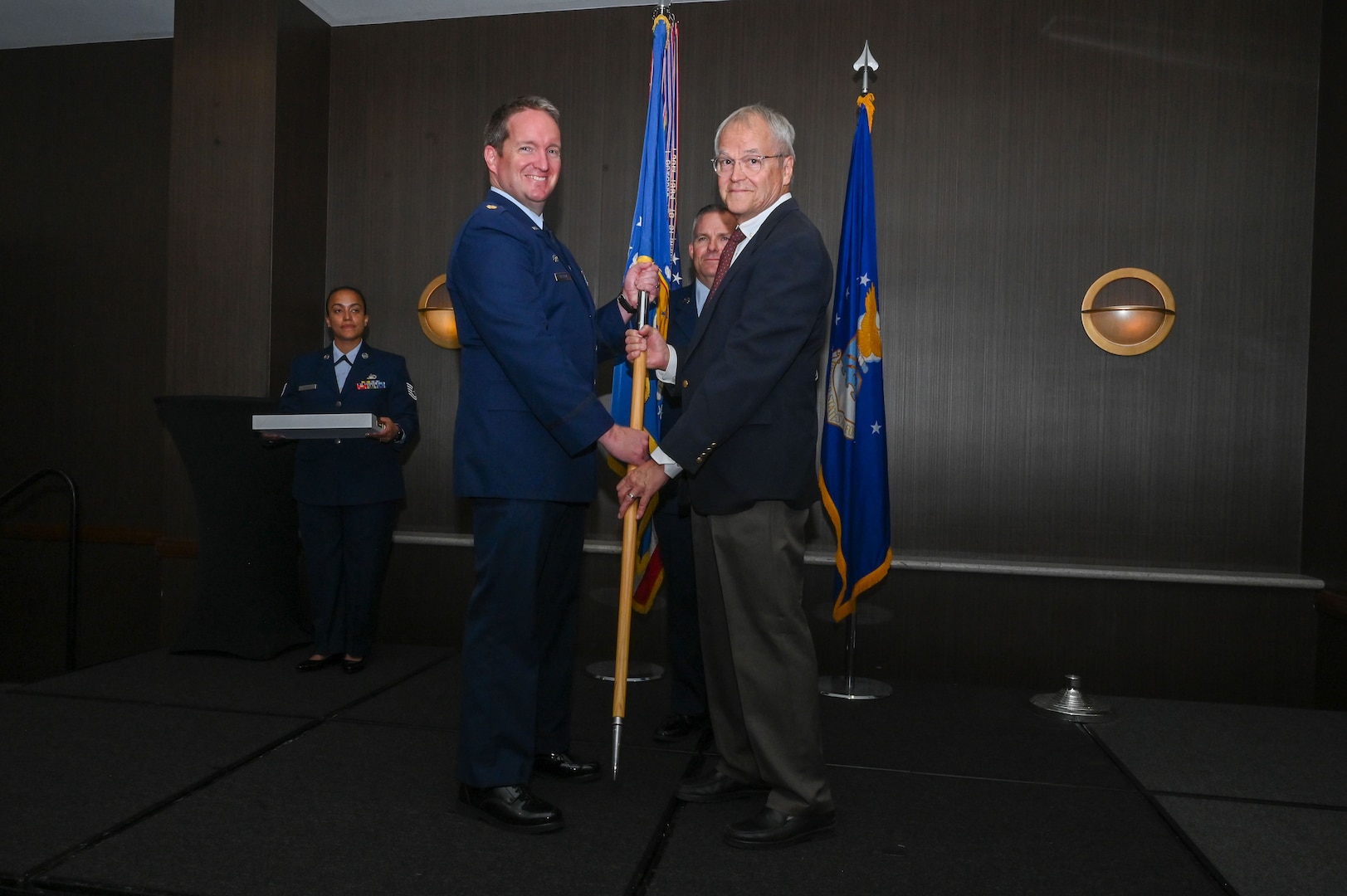 Maj. Alexander Williams, 433rd Contingency Response Flight commander, hands the 433rd Airlift Wing guidon to Duane Paulson, San Antonio independent consultant, during the 433rd AW 2025 Honorary Commanders’ Induction Ceremony in San Antonio, June 7, 2025.