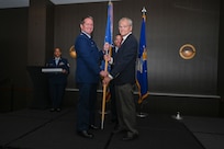 Maj. Alexander Williams, 433rd Contingency Response Flight commander, hands the 433rd Airlift Wing guidon to Duane Paulson, San Antonio independent consultant, during the 433rd AW 2025 Honorary Commanders’ Induction Ceremony in San Antonio, June 7, 2025.