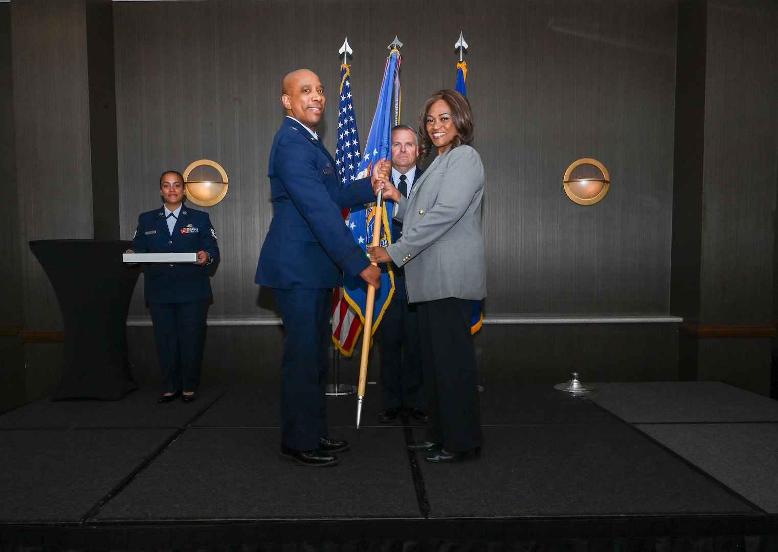 Lt. Col. Jason Cockrell, 68th Airlift Squadron commander, hands the 433rd Airlift Wing guidon to Vanessa J-Douglas, Masters Leadership Program San Antonio board of directors, during the 433rd AW 2025 Honorary Commanders’ Induction Ceremony in San Antonio, June 7, 2025.