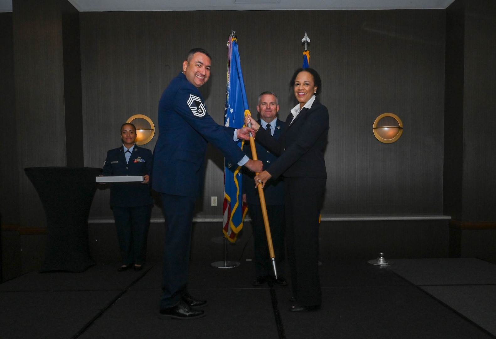 Chief Master Sgt. Samuel Strawbridge, 356th Airlift Squadron senior leader, hands the 433rd Airlift Wing guidon to Michelle Hoskins, Reaching Maximum Independence president, during the 433rd AW 2025 Honorary Commanders’ Induction Ceremony in San Antonio, June 7, 2025.