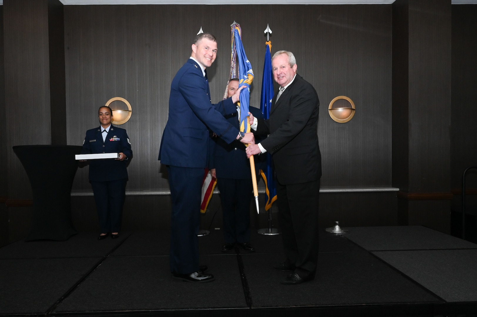 Maj. Aleksander Layne, 433rd Logistics Readiness Squadron commander, hands the 433rd Airlift Wing guidon to Jay Gilmore, SWBC Mortgage Company senior loan officer, during the 433rd AW 2025 Honorary Commanders’ Induction Ceremony in San Antonio, June 7, 2025.