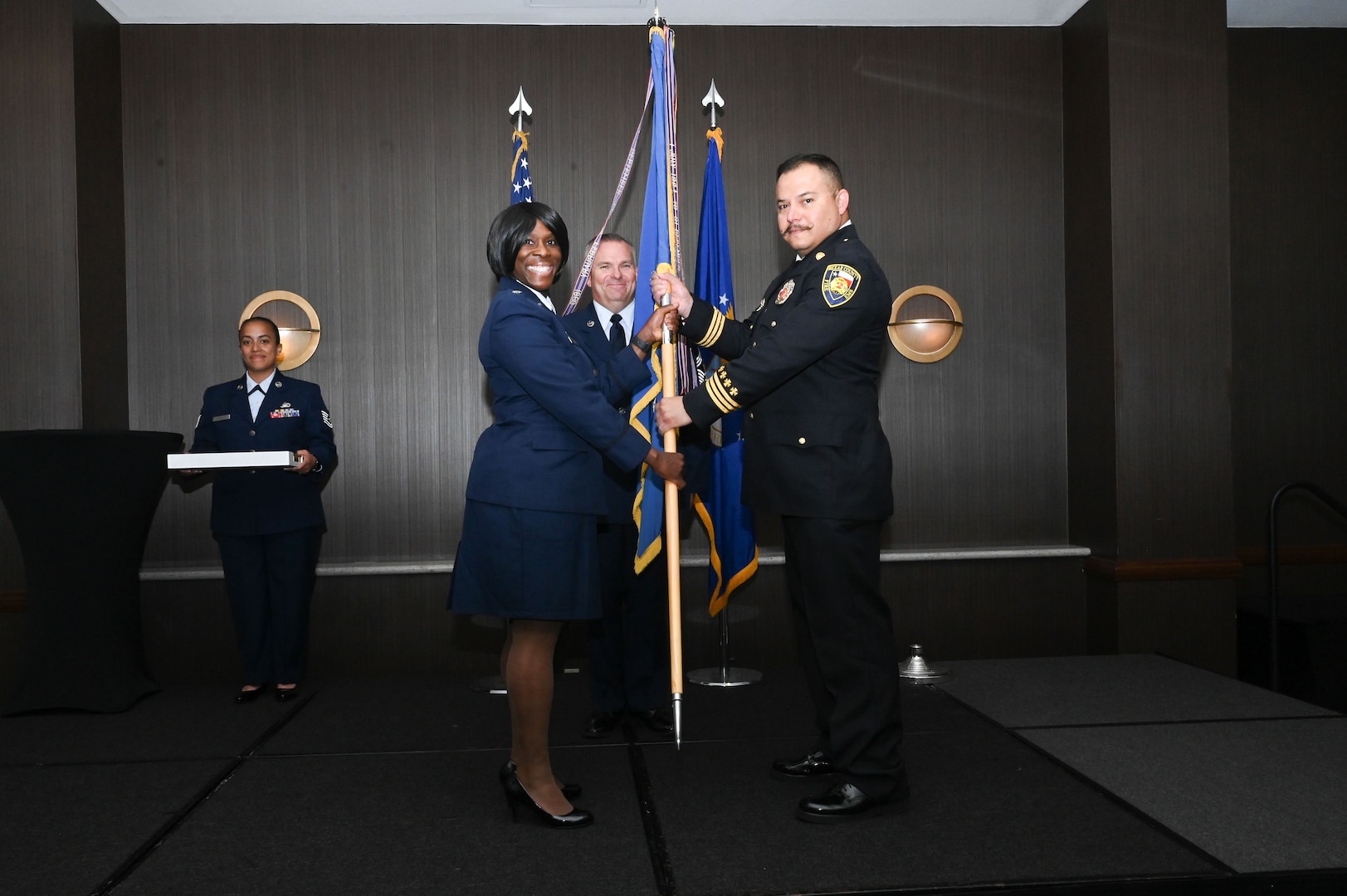 Lt. Col. Teanglia Moore, 26th Aerial Port Squadron commander, hands the 433rd Airlift Wing guidon to Rudy Khalaf, Bexar County division chief of fire protection, during the 433rd AW 2025 Honorary Commanders’ Induction Ceremony in San Antonio, June 7, 2025.