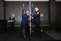 Lt. Col. Teanglia Moore, 26th Aerial Port Squadron commander, hands the 433rd Airlift Wing guidon to Rudy Khalaf, Bexar County division chief of fire protection, during the 433rd AW 2025 Honorary Commanders’ Induction Ceremony in San Antonio, June 7, 2025.