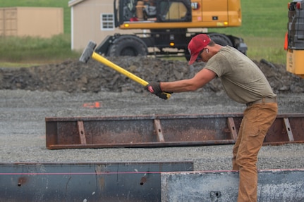Airman 1st Class Nicholas Vallario, pavements and construction equipment specialist with the 201st RED HORSE Detachment 1, constructs a Rapid Airfield Damage Repair system at Fort Indiantown Gap, Pennsylvania, June 6, 2025. This mock runway will be used as a training asset for the Air National Guard Schoolhouse, operated by the 193rd Special Operations Wing, to help civil engineering Airmen learn how to quickly repair an airfield in combat situations. (U.S. Air Force photo by Airman Austin Stern)