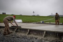 Staff Sgt. Kyson Edwards, left, a heavy equipment operator with the 201st RED HORSE Squadron and Staff Sgt. Emilio Ocampo, a pavements and construction specialist with the 820th RED HORSE Squadron, finishes a concrete surface during the construction of a Rapid Airfield Damage Repair system at Fort Indiantown Gap, Pennsylvania, June 9, 2025. The mock runway will be used as a training asset for the Air National Guard Schoolhouse, operated by the 193rd Special Operations Wing, to help civil engineering Airmen learn how to rapidly repair an airfield in combat situations. (U.S. Air National Guard photo by Tech. Sgt. Tony Harp)
