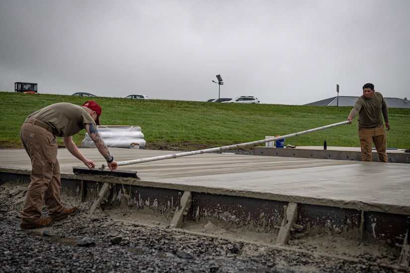 Staff Sgt. Kyson Edwards, left, a heavy equipment operator with the 201st RED HORSE Squadron and Staff Sgt. Emilio Ocampo, a pavements and construction specialist with the 820th RED HORSE Squadron, finishes a concrete surface during the construction of a Rapid Airfield Damage Repair system at Fort Indiantown Gap, Pennsylvania, June 9, 2025. The mock runway will be used as a training asset for the Air National Guard Schoolhouse, operated by the 193rd Special Operations Wing, to help civil engineering Airmen learn how to rapidly repair an airfield in combat situations. (U.S. Air National Guard photo by Tech. Sgt. Tony Harp)