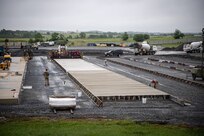 Airmen from various civil engineering specialties construct a Rapid Airfield Damage Repair system at Fort Indiantown Gap, Pennsylvania, June 9, 2025. The mock runway will be used as a training asset for the Air National Guard Schoolhouse, operated by the 193rd Special Operations Wing, to help civil engineering Airmen learn how to rapidly repair an airfield in combat situations. (U.S. Air National Guard photo by Tech. Sgt. Tony Harp)