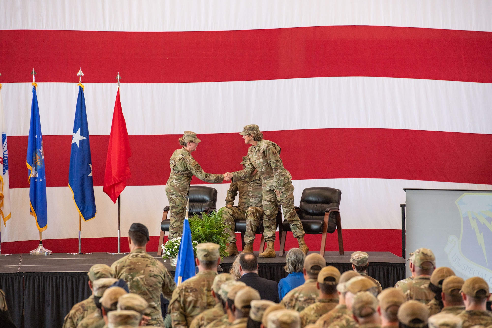 A woman shakes hands with another military member