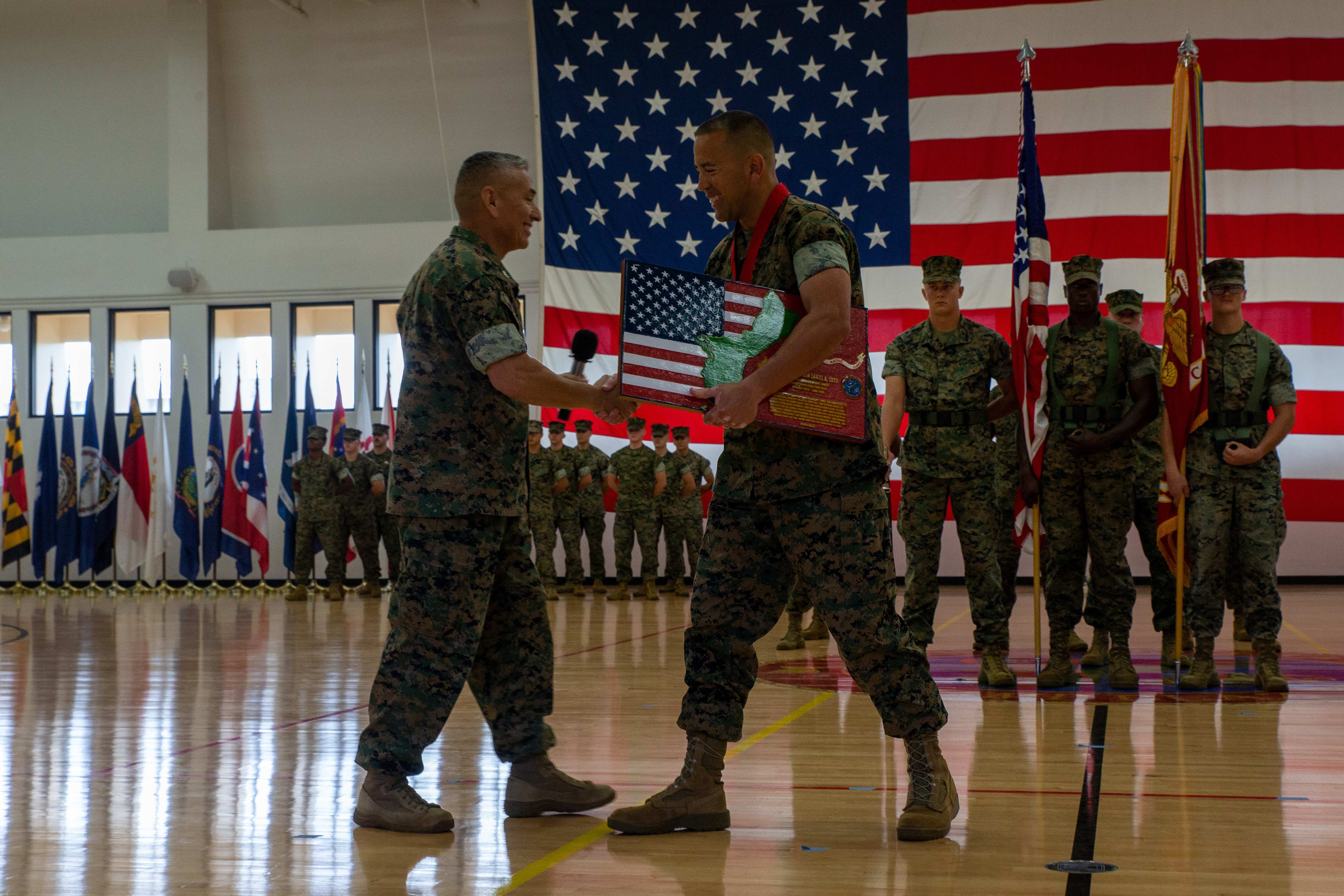 U.S. Marine Corps Col. Ernest Govea, commanding officer, Marine Corps Base Camp Blaz, presents a plaque and shakes hands with Sgt. Maj. Daniel A. Soto, out-going sergeant major, MCB Camp Blaz, during a relief ceremony at MCB Camp Blaz, Guam, June 11, 2025. Soto, MCB Camp Blaz’s first sergeant major, relinquished his duties during a ceremony aboard the installation. (U.S. Marine Corps photo by Lance Cpl. Afton Smiley)