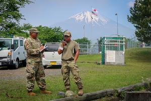 Airman speaks through radio while other Airman speaks.