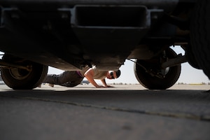 Airman lays under an Air Conditioning Cart on a flightline