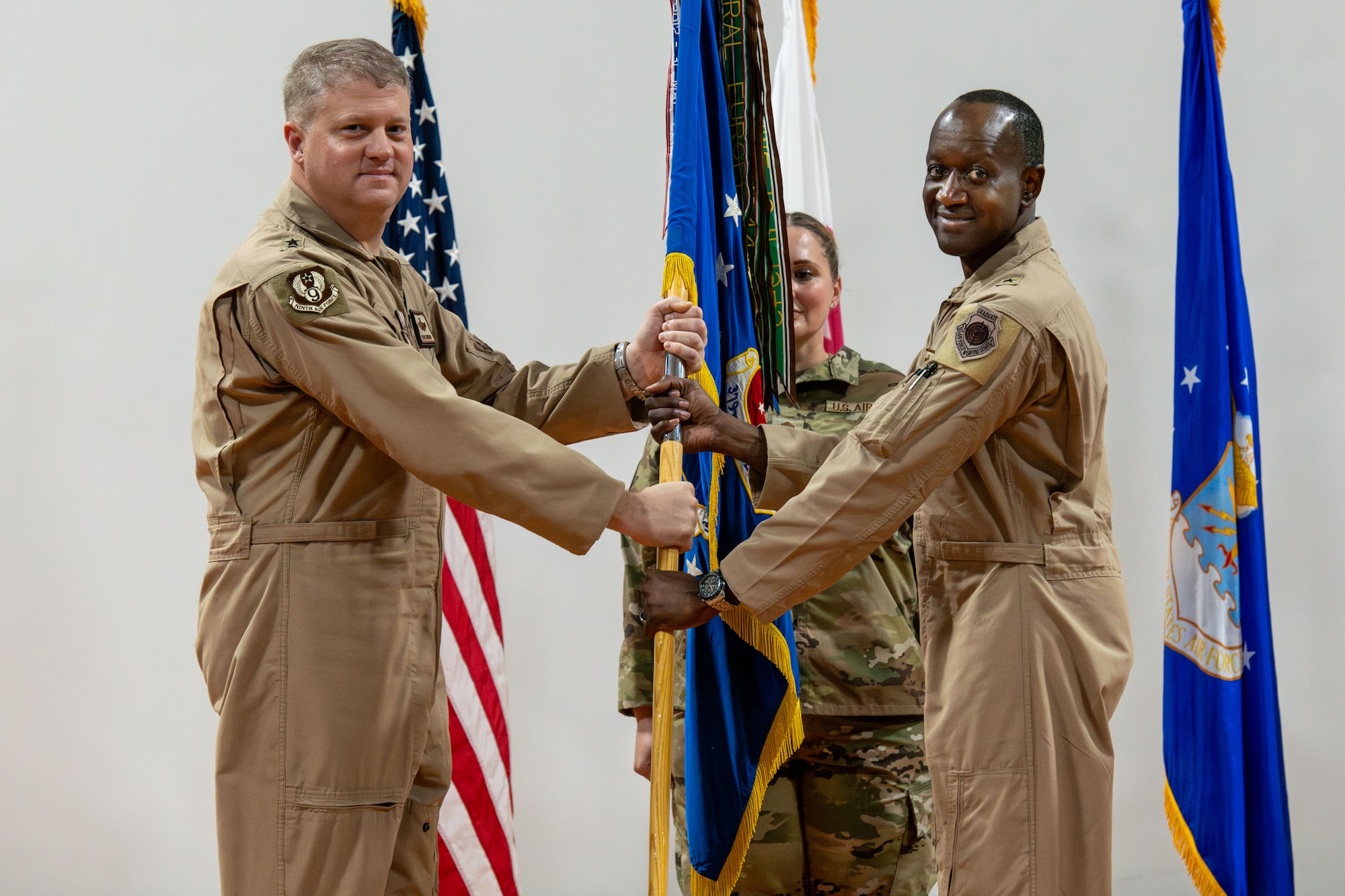 U.S. Air Force Brig. Gen. Travis Edwards, right, 379th Air Expeditionary Wing incoming commander, receives the 379th AEW guidon from Maj. Gen. David Shoemaker, 9th Air Force (Air Forces Central) deputy commander, during the 379th AEW Change of Command Ceremony within the U.S. Central Command area of responsibility, June 9, 2025. The 379th AEW provides support to more than 5,400 Air Force, joint and coalition force partners. (U.S. Air Force photo by Staff Sgt. Sean Moriarty)