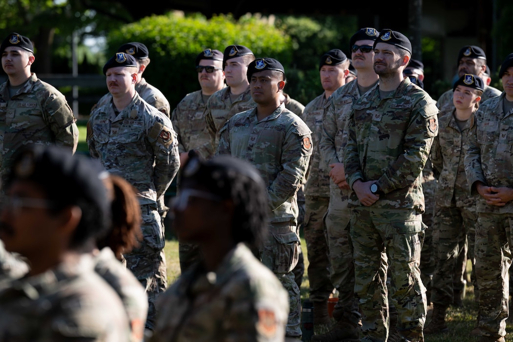 Gathered Airmen standing in a formation listen to a speech at an outdoor ceremony.