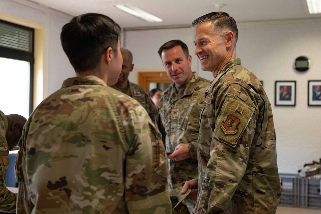 Two Airmen discuss with a weapons firing instructor in a classroom setting.