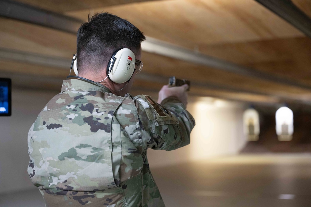 An Airman fires a handgun at an indoor shooting range.