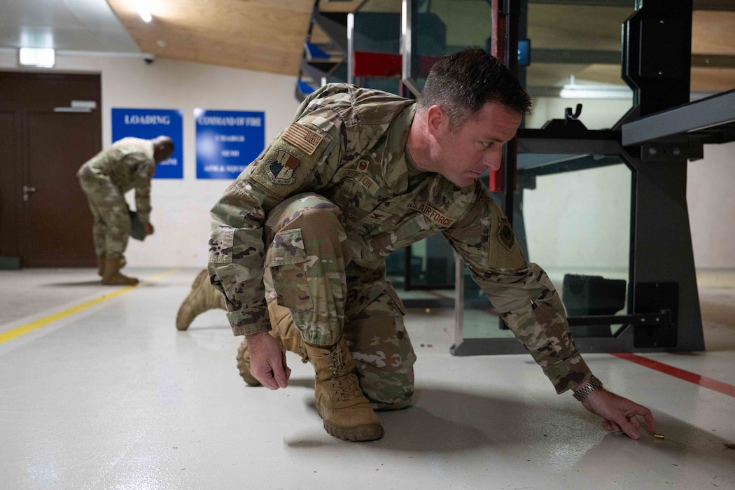 An Airman picks up spent ammunition casings at an indoor shooting range.