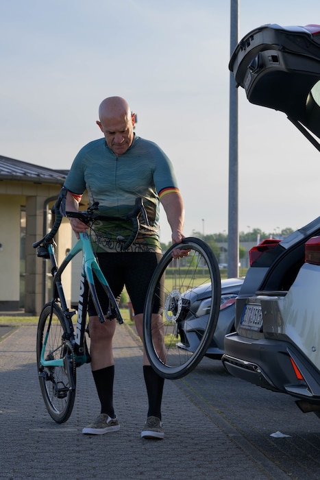A cyclist assembles his bicycle in a parking lot.