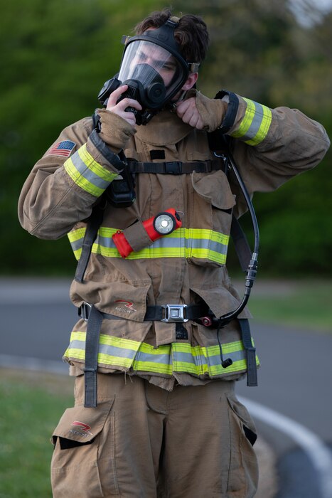 A firefighter dons his protective gas mask while wearing firefighting gear.