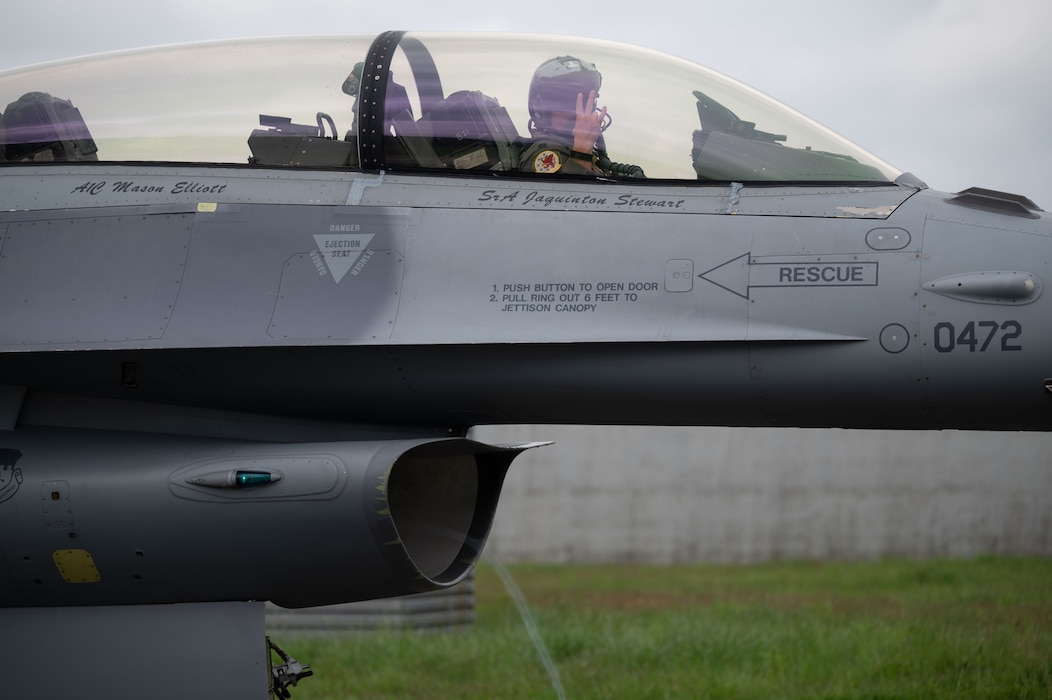 A pilot signals to the ground crew from inside the cockpit of his fighter aircraft.